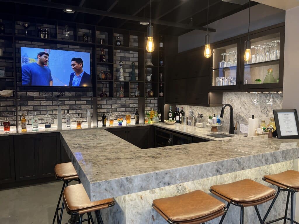 Modern home bar featuring a polished stone countertop and coordinating stone backsplash with built-in shelving