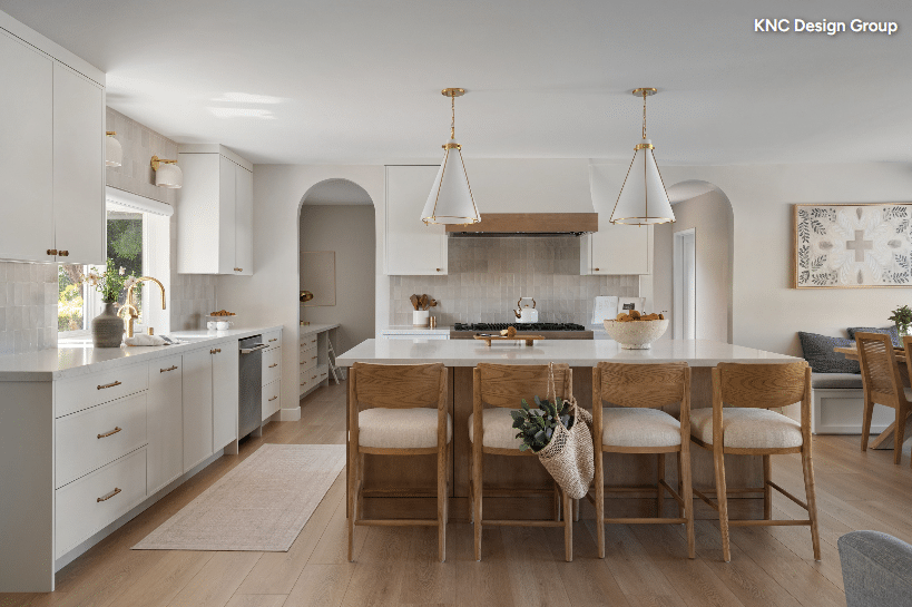 Bright open kitchen with white cabinetry, a large island with seating, and brass pendant lights above the island.