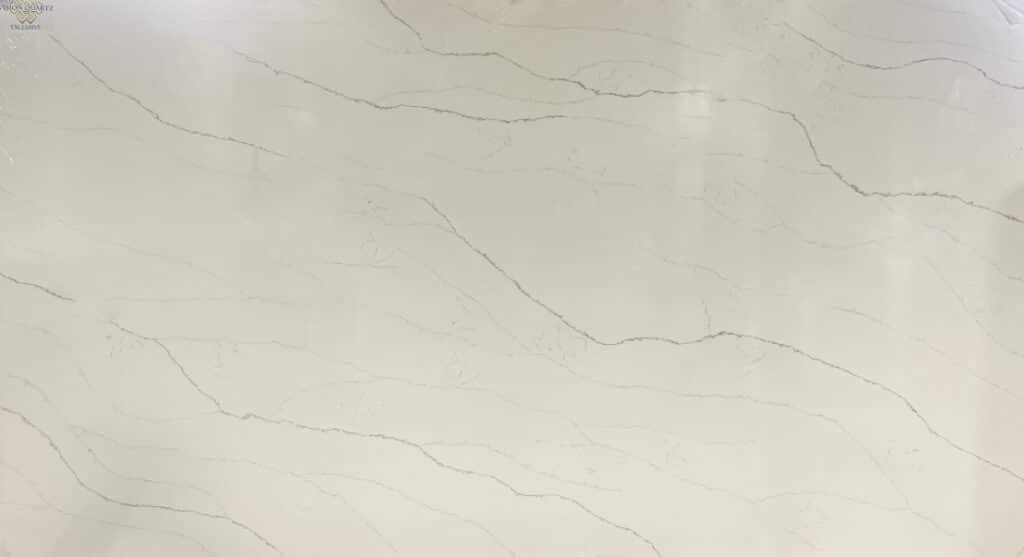 White marble slab with pale gray veining and a small Vision Quartz Exclusive logo in the top-left corner.